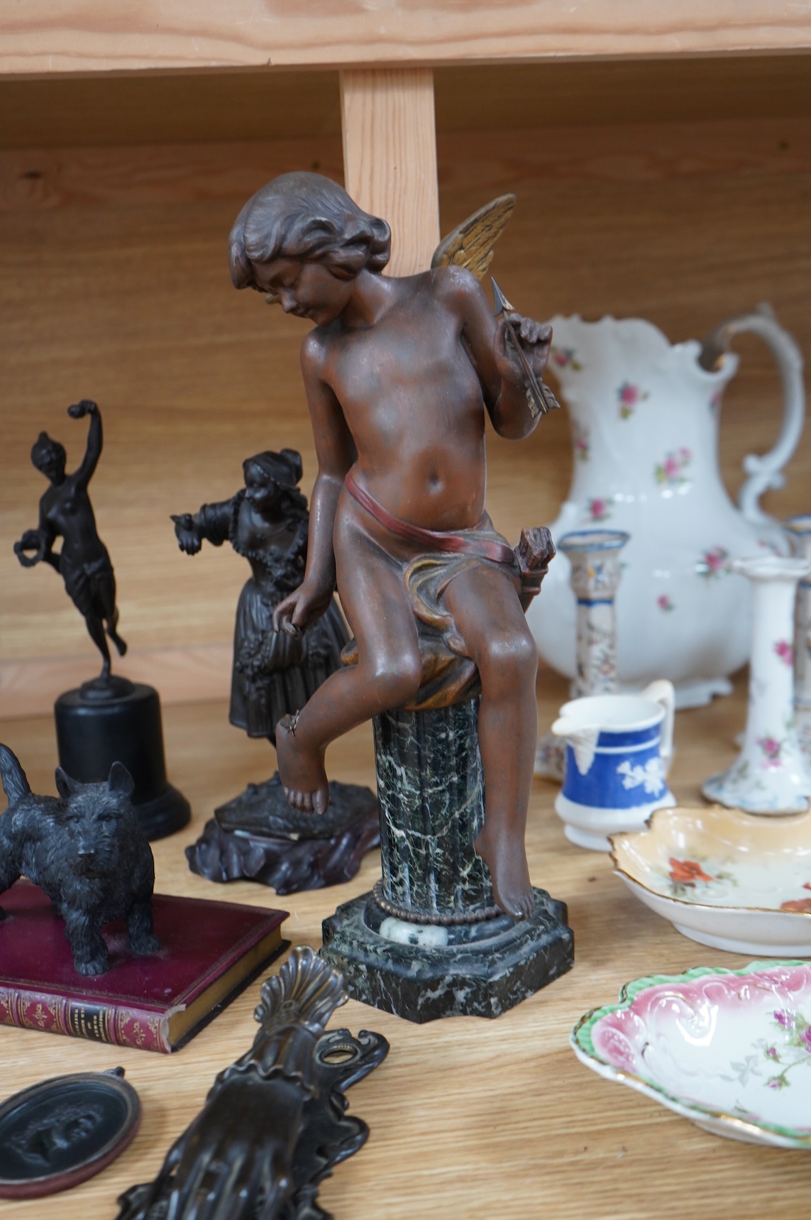 A bronzed spelter angel on column plinth, 38cm high, two other figures, a model of a dog on a book, a letter clip and an oval classical plaque. (6).